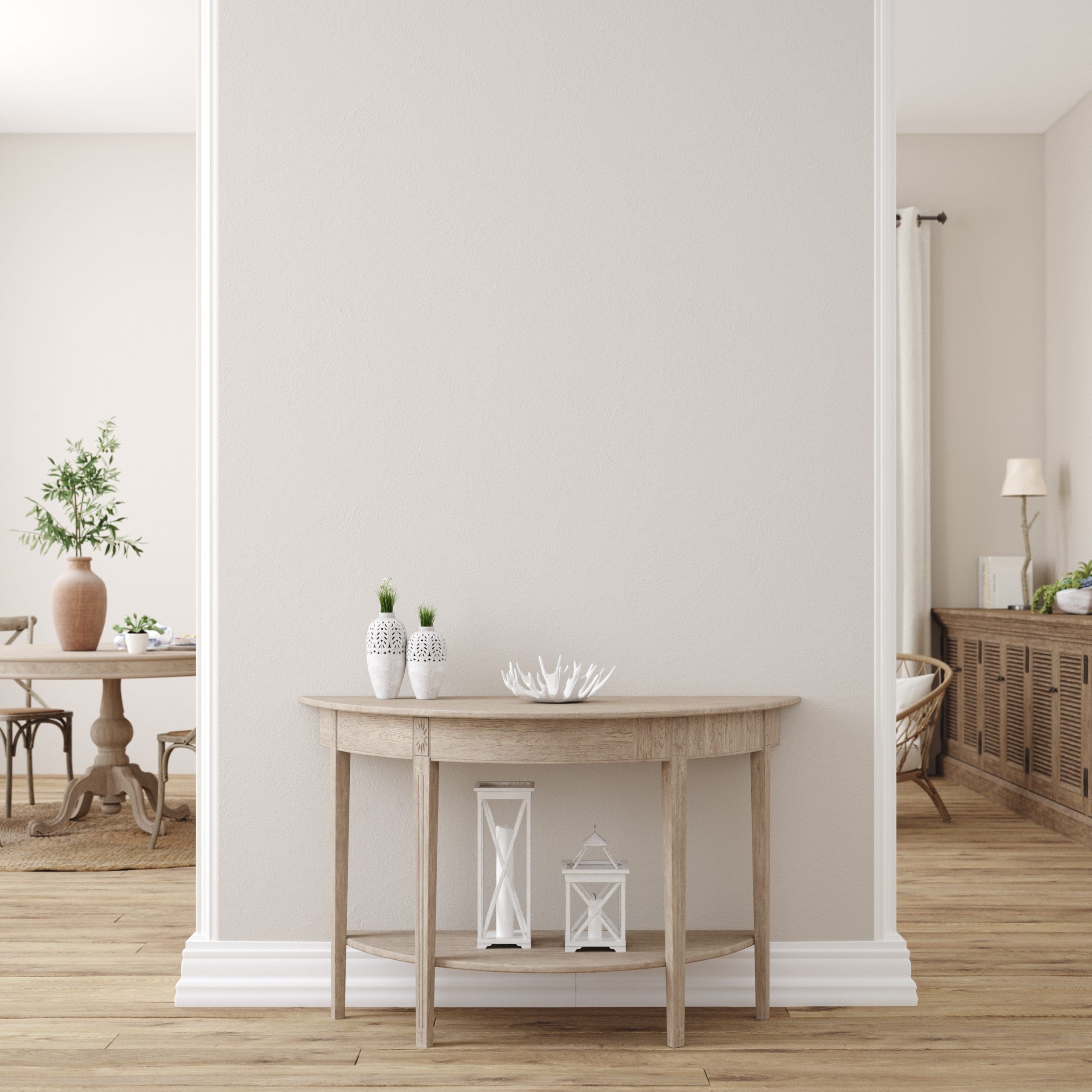 A minimal wooden console table against a light beige wall, decorated with two small plants, white decorative coral, and two lanterns on the lower shelf. A bright, airy room with wooden floors is visible in the background.